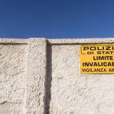 E' protetto da una lungo muro di cinta sul quale � fissato un cartello giallo con su scritto: �Polizia di Stato. Limite invalicabile. Vigilanza armata�